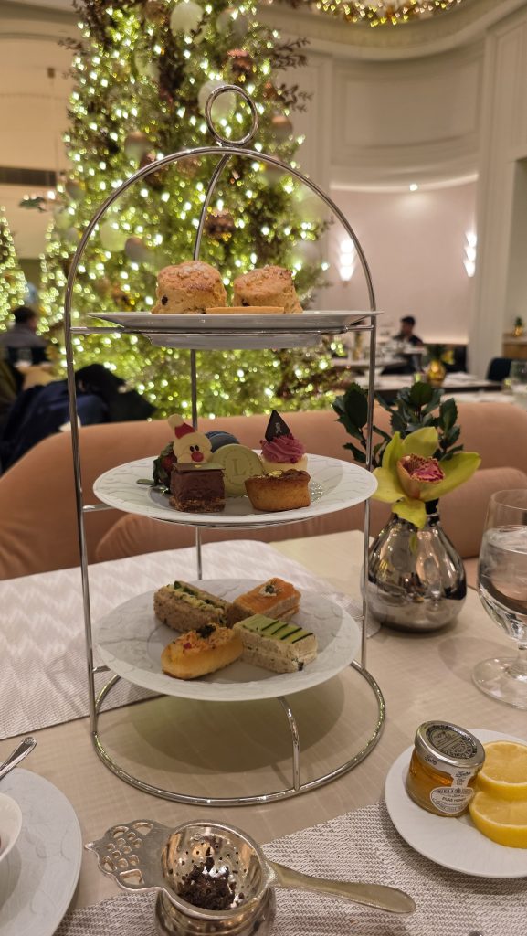 Tiered stand with savories, sweets, and scones at St. Regis New York Ladurée afternoon tea, with holiday tree behind