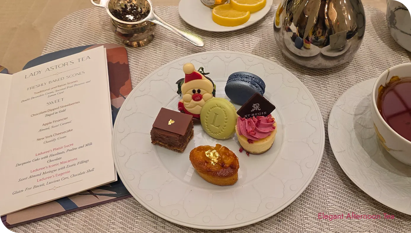 Dessert plate from the St. Regis New York holiday afternoon tea with macarons, chocolate, and small pastries beside a teacup and teapot