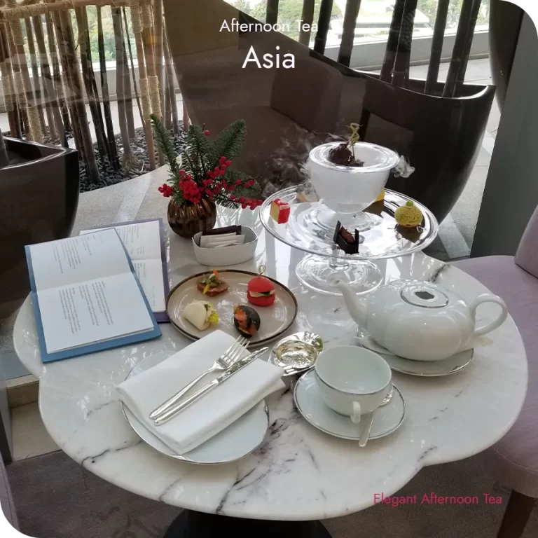 Afternoon tea table in Asia with a marble setting, porcelain teaware, composed savories, and a dessert presented with a visible dry ice reveal.