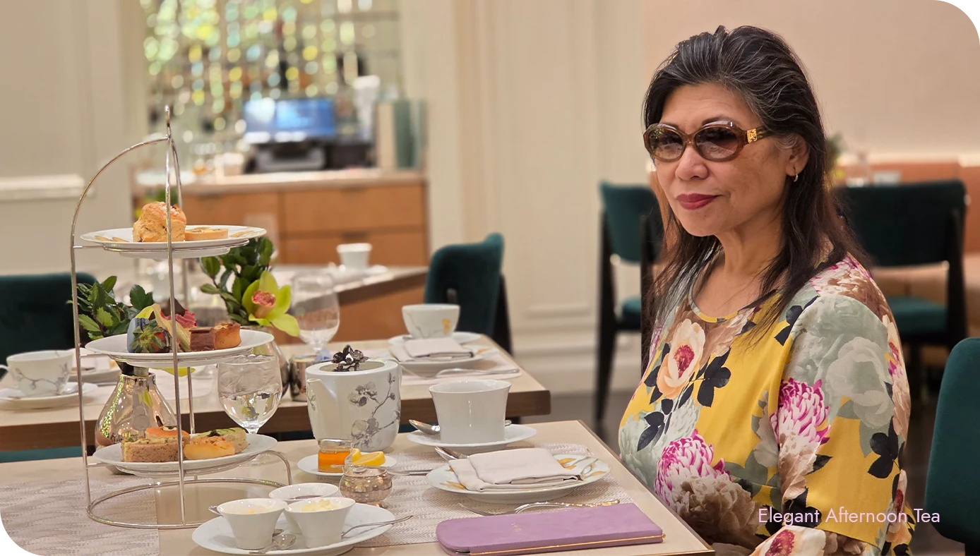 Guest seated at an afternoon tea table at The St. Regis New York with a full tiered stand and tea service