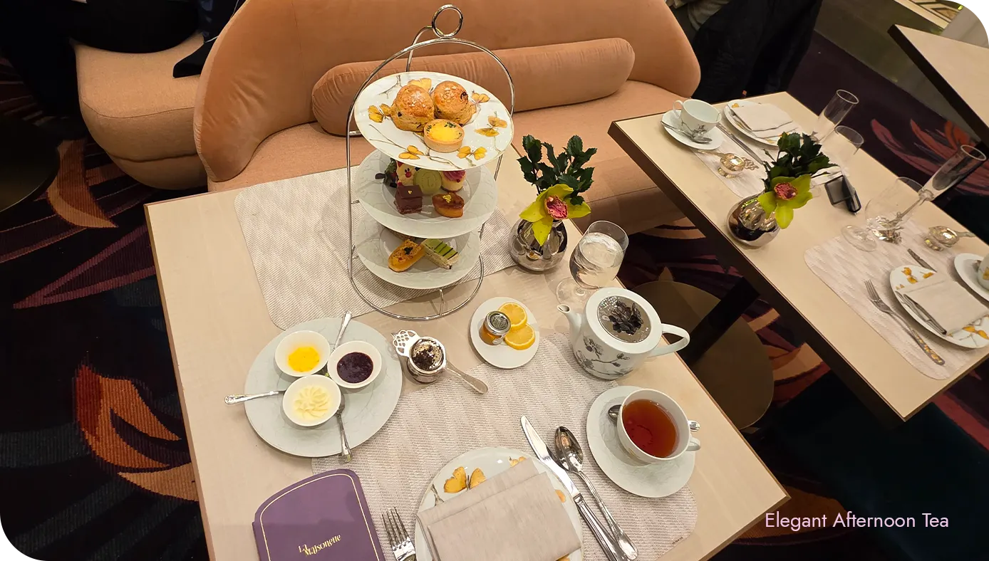 Wide view of the St. Regis New York holiday afternoon tea set with tiered stand, tea service, and desserts on the table