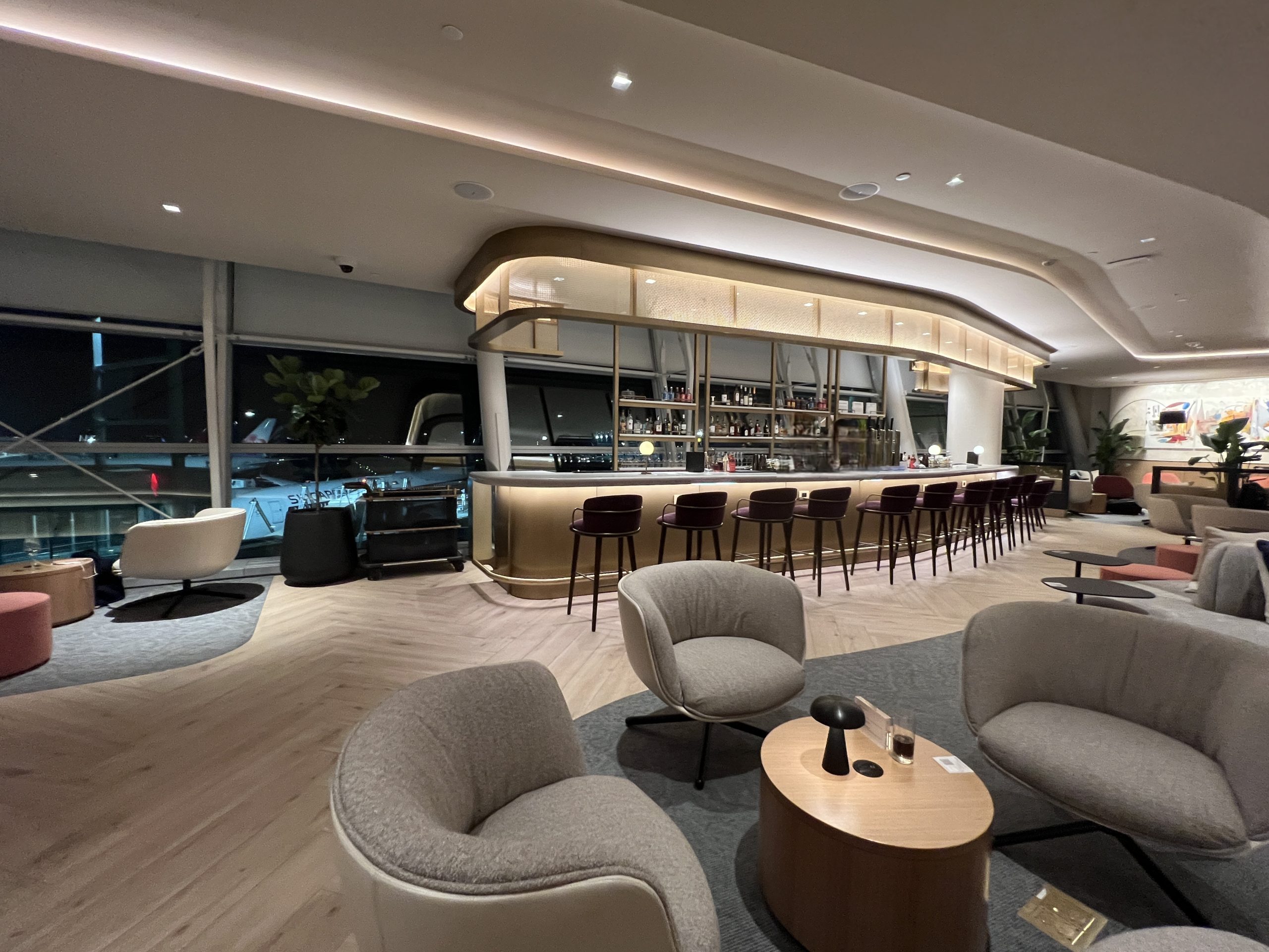 Bar counter with tall stools and backlit canopy lighting in the Sapphire Lounge at JFK