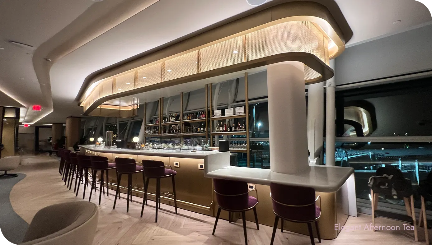 Bar counter with tall stools and backlit canopy lighting in the Sapphire Lounge at JFK
