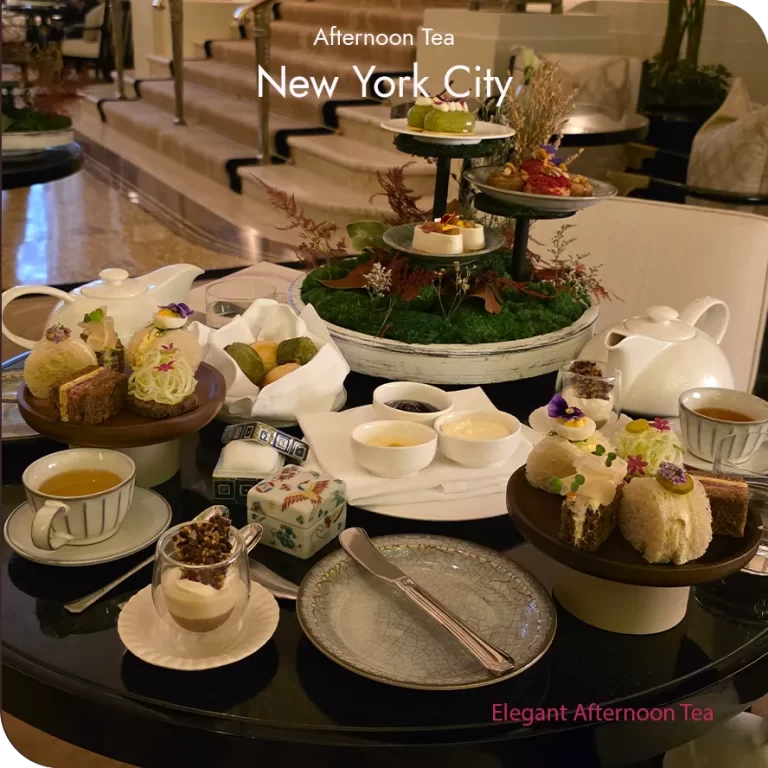 Afternoon tea table setting in New York City with tiered stand, teapots, and petite savories and sweets.