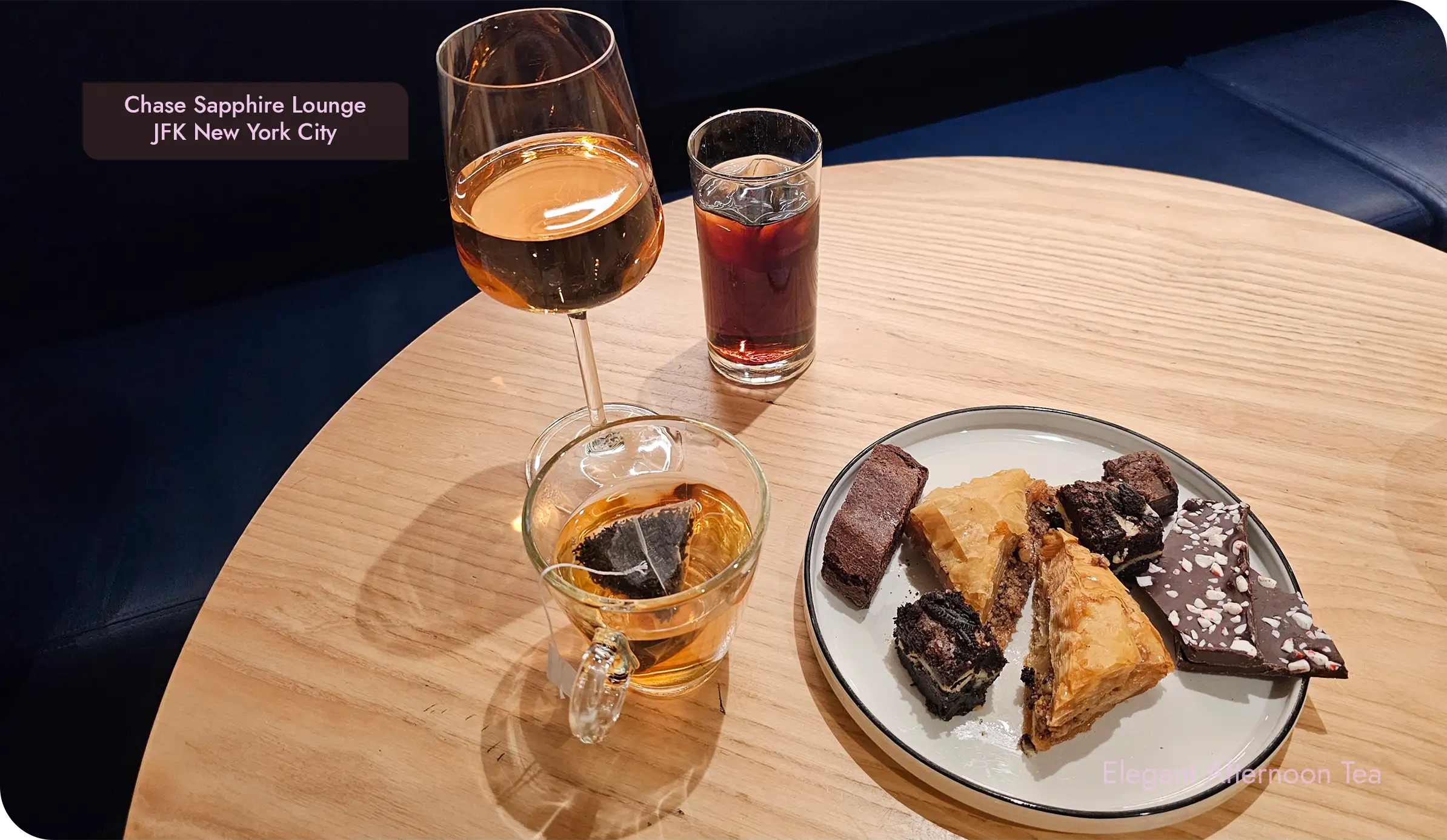 Tea, a rosé wine, and a dessert plate on a wood table at the Sapphire Lounge in JFK